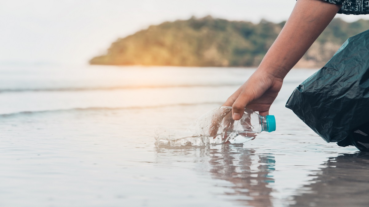 Hand picking up plastic bottle cleaning on the beach , volunteer concept.