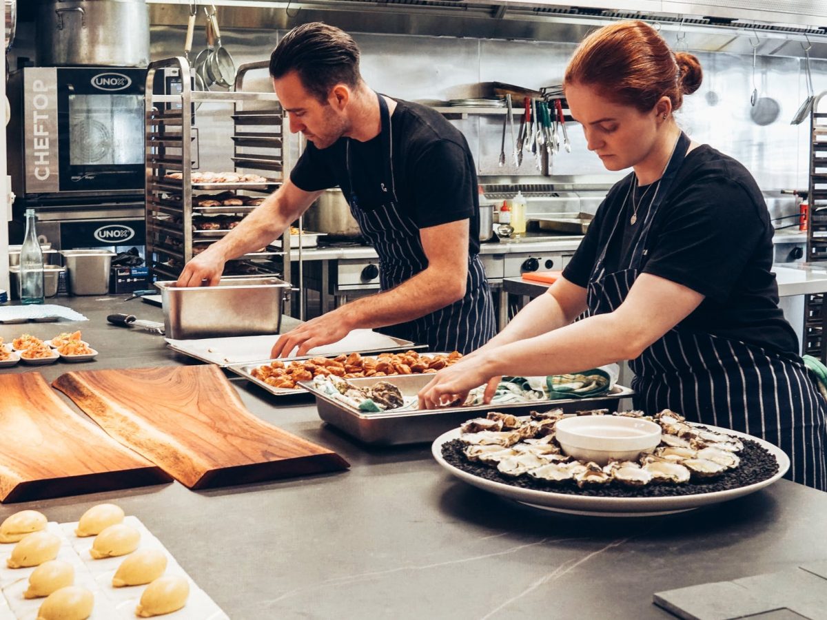 man and woman wearing black and white striped aprons cooking