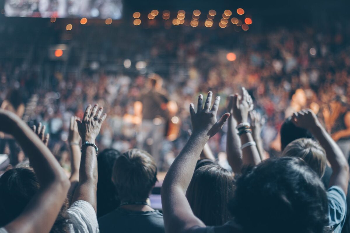 group of people raise their hands on stadium