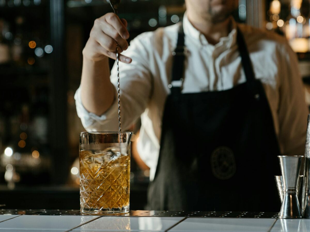 man in white shirt holding clear drinking glass